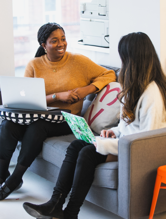 Juno Instructor and career specialist Chi-Chi Egbo has a conversation with a student on a grey couch