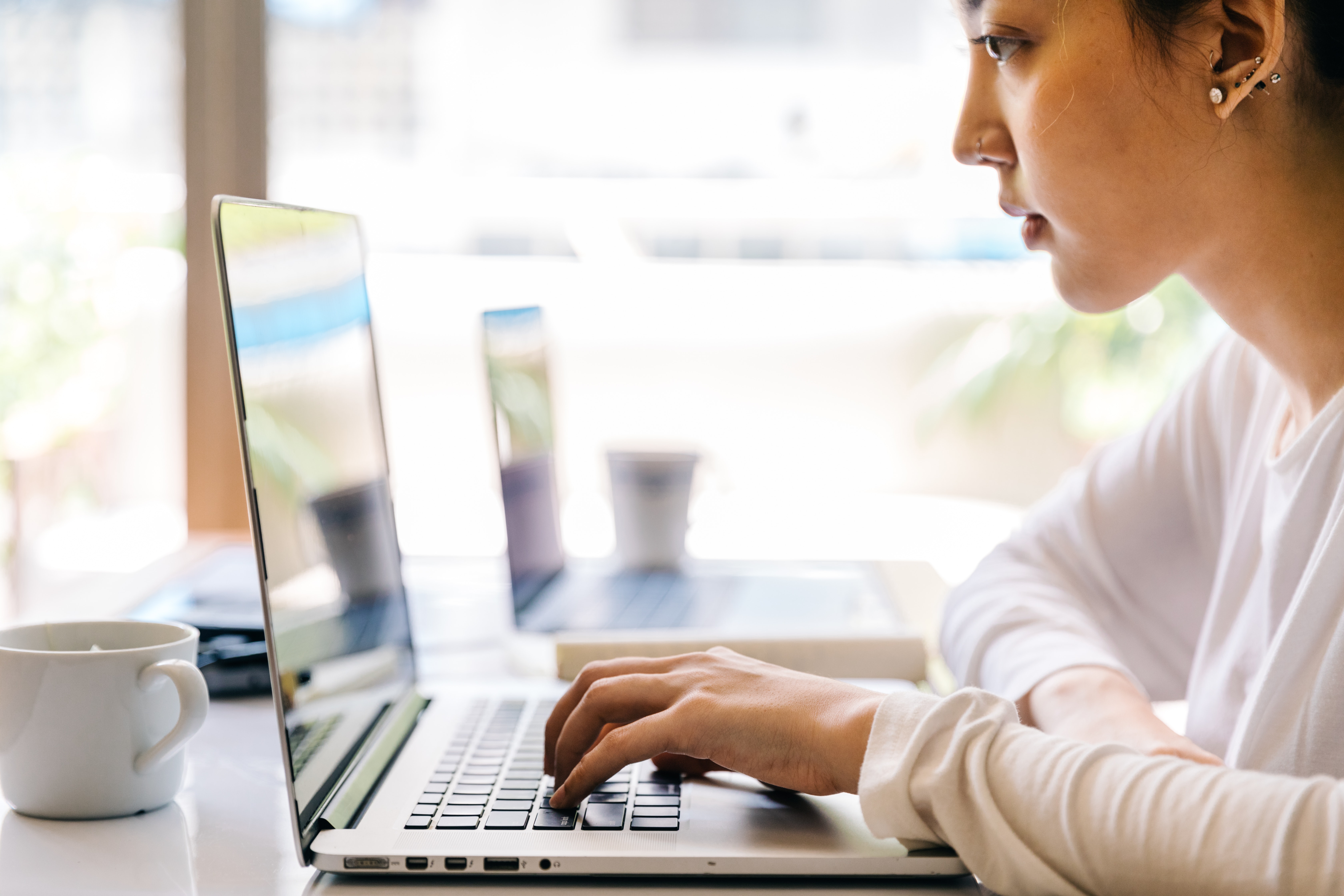 Woman learning to code on a laptop in a cafe
