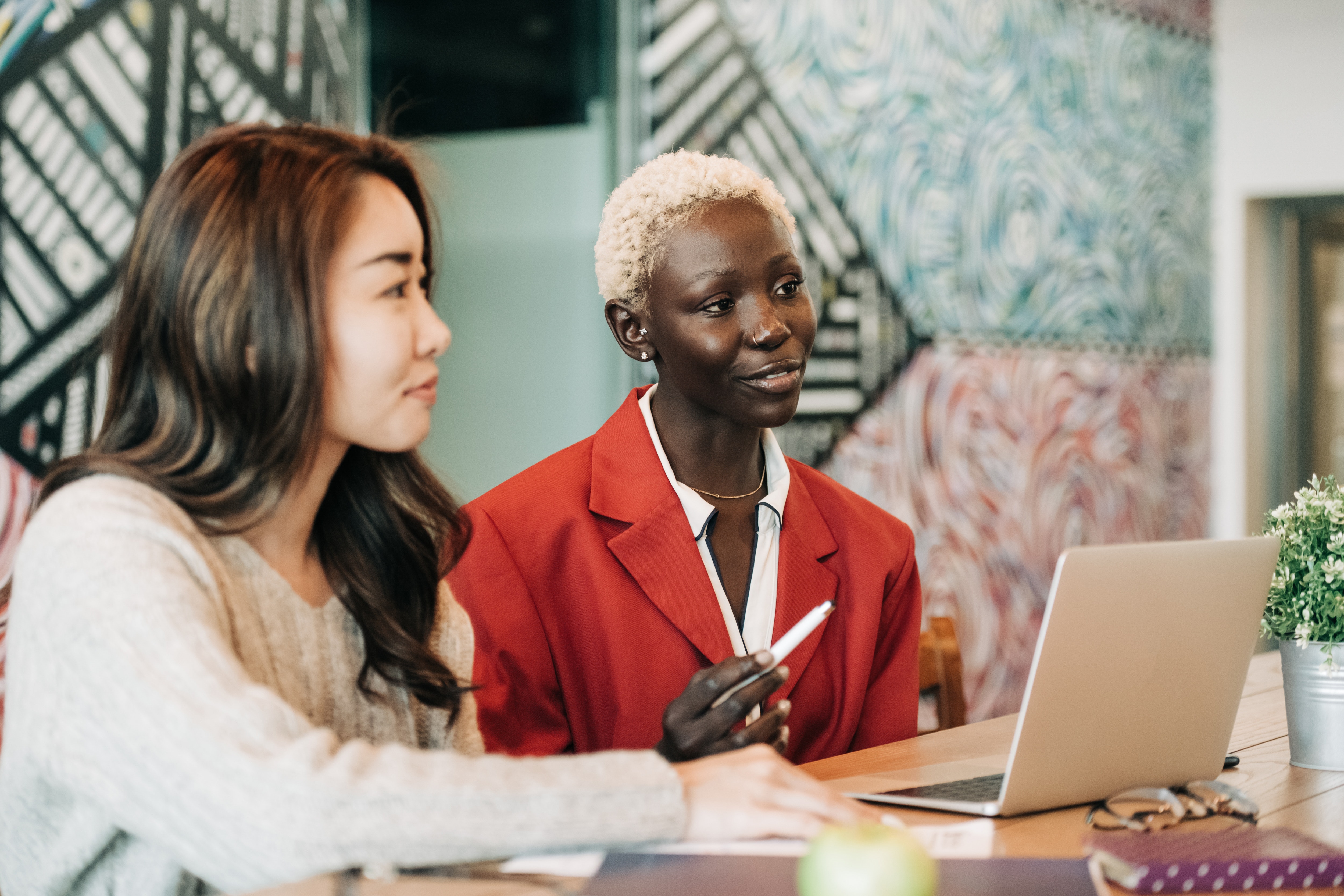 Two professional women sitting in a funky meeting room with a laptop