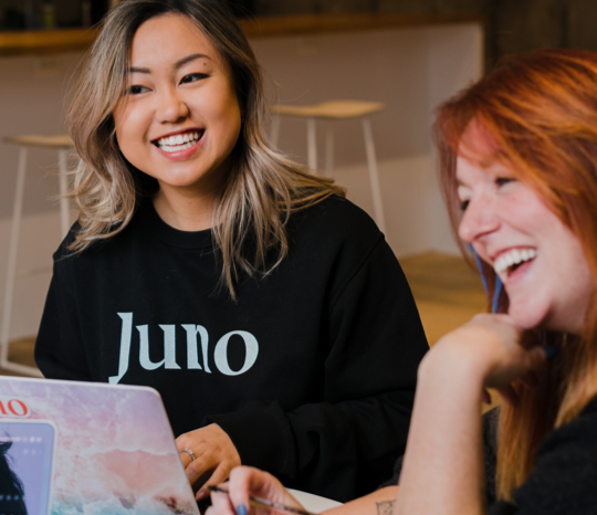Two Juno College students are laughing and looking off to the left