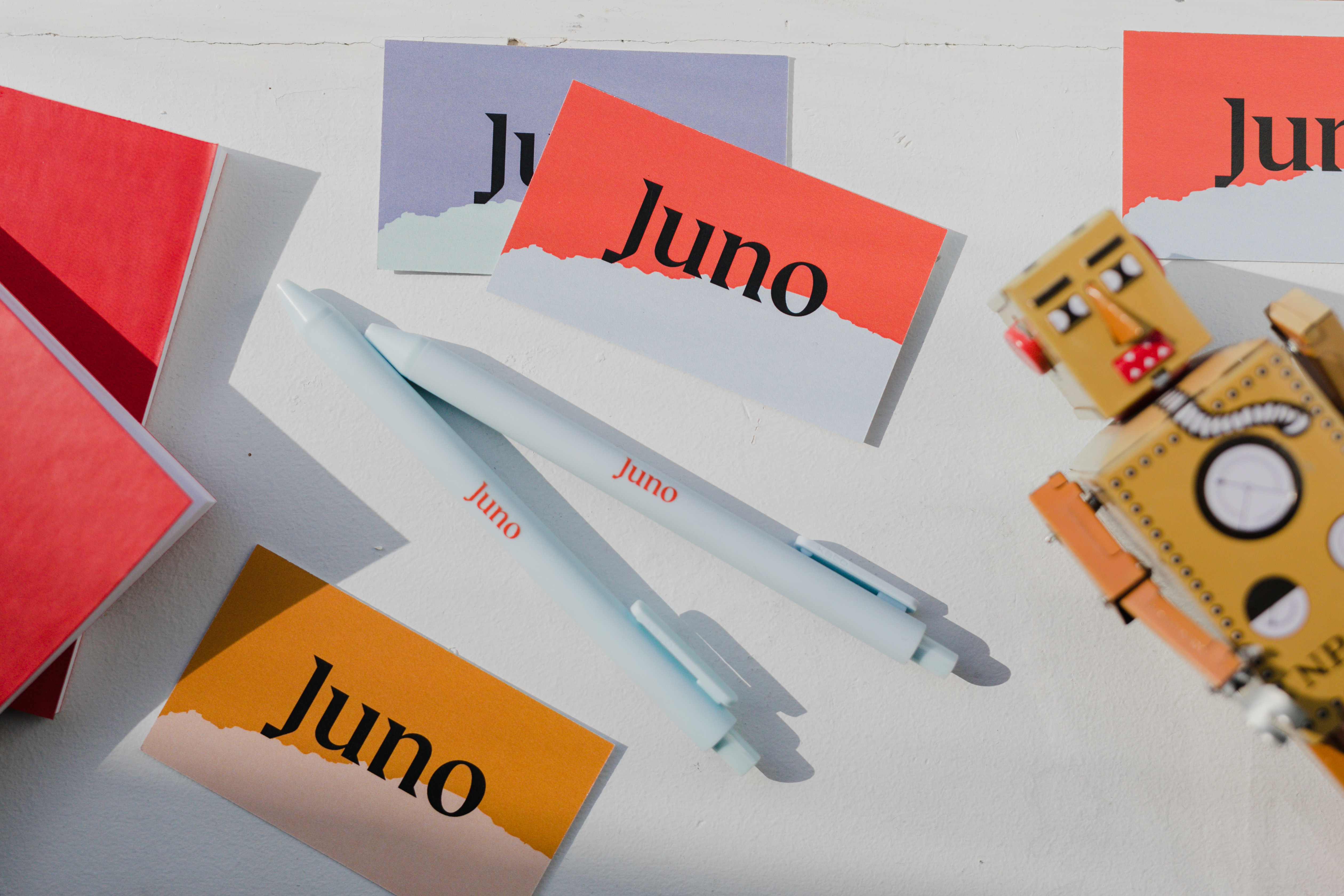 Spread of Juno-branded business cards and pens, and a toy robot.