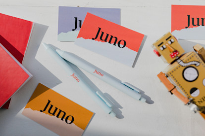 Spread of Juno-branded business cards and pens, and a toy robot.