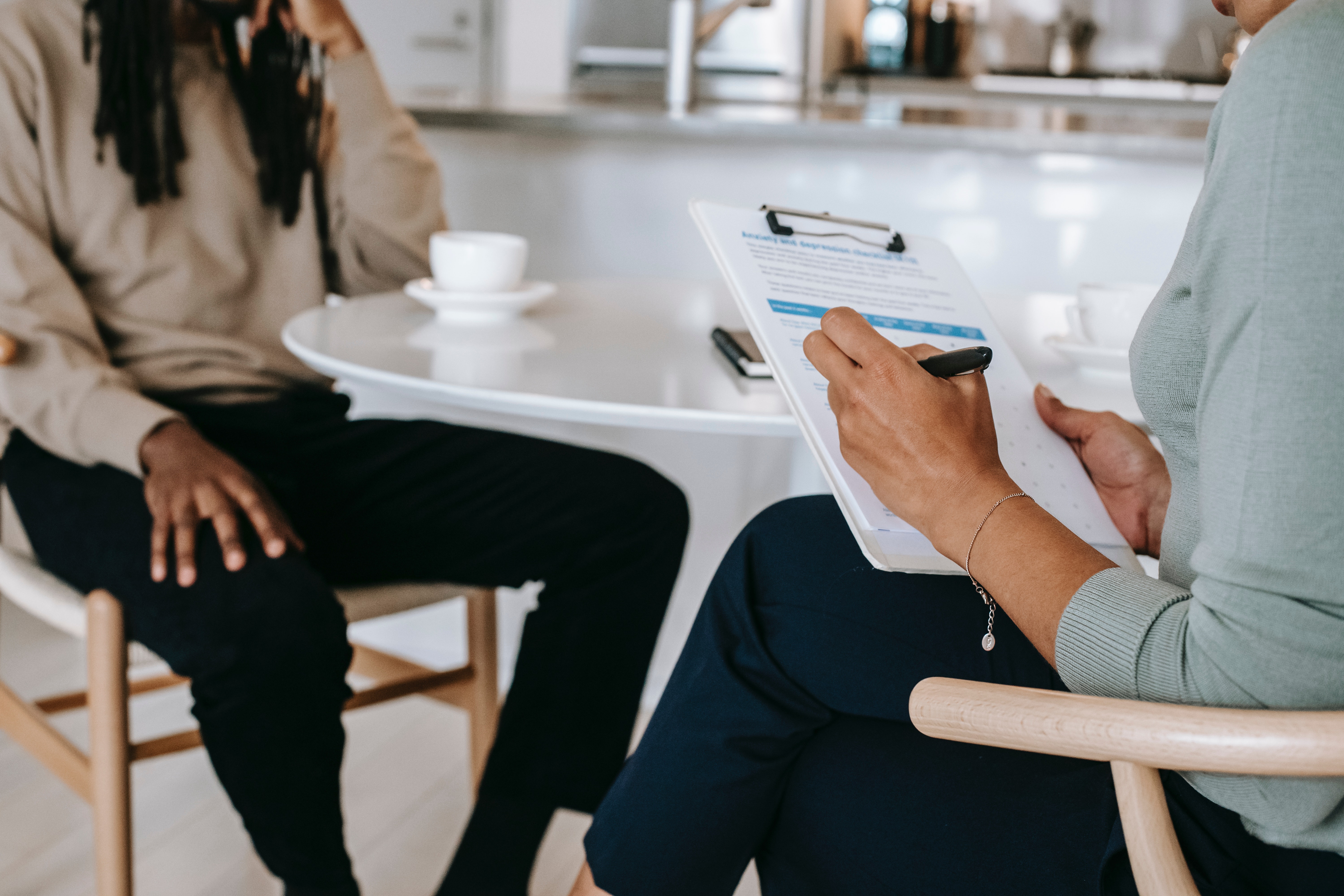 Man and women sit across each other. Women has a clipboard in hand