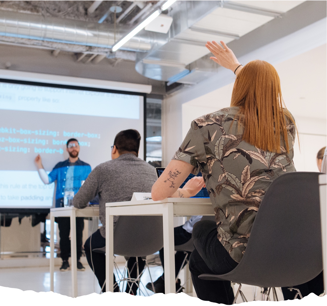 An in-person classroom setting at Juno College with an instructor at the front and a student raising their hand.