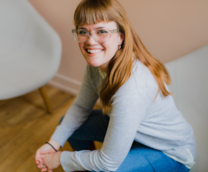 Juno college student with long red hair and glasses smiling at the camera