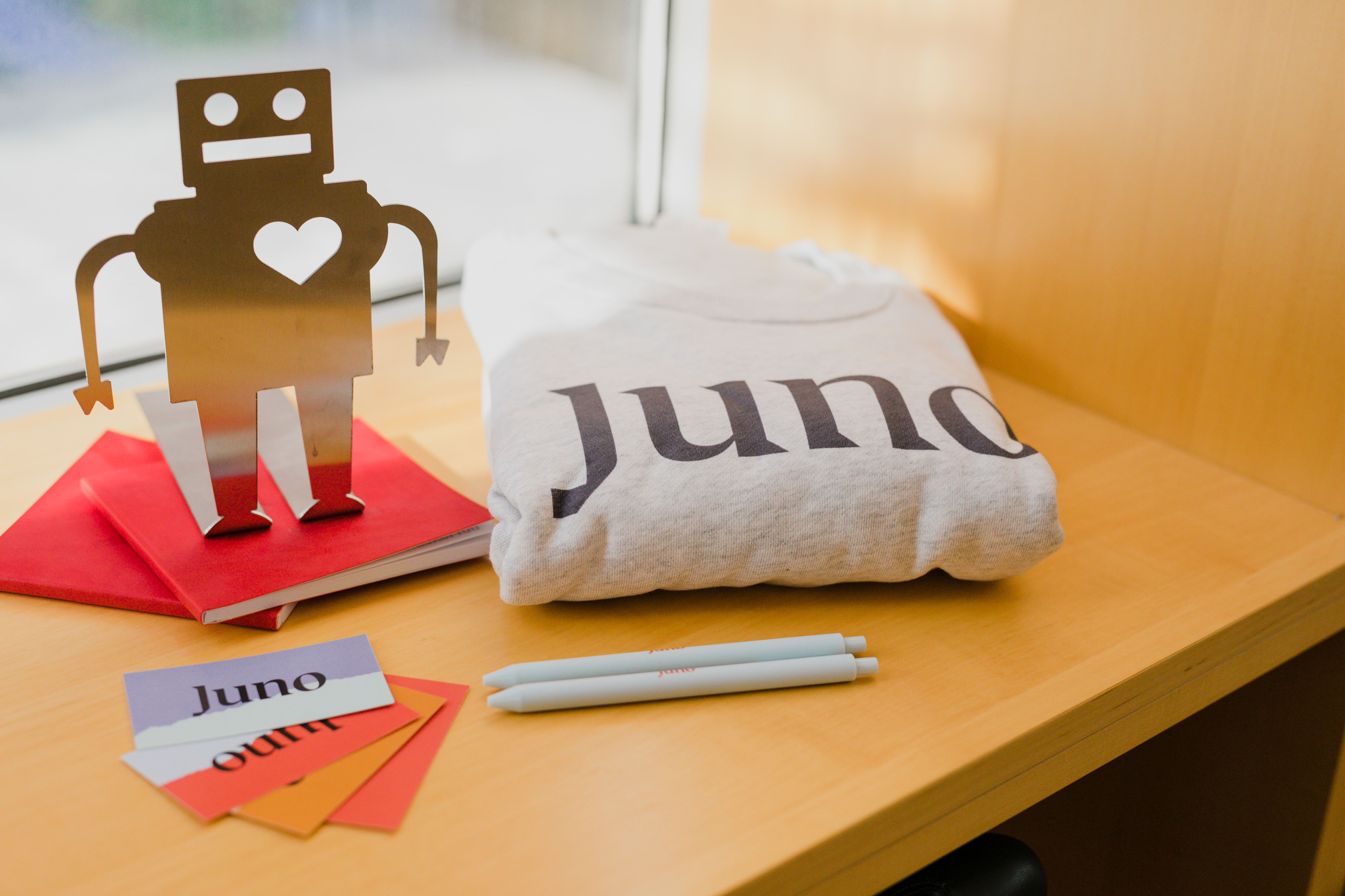 A robot figuring next to a Juno-branded sweater, notebooks, pens, and business cards.