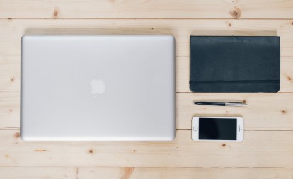 Macbook, notebook, pen, and cellphone on desk