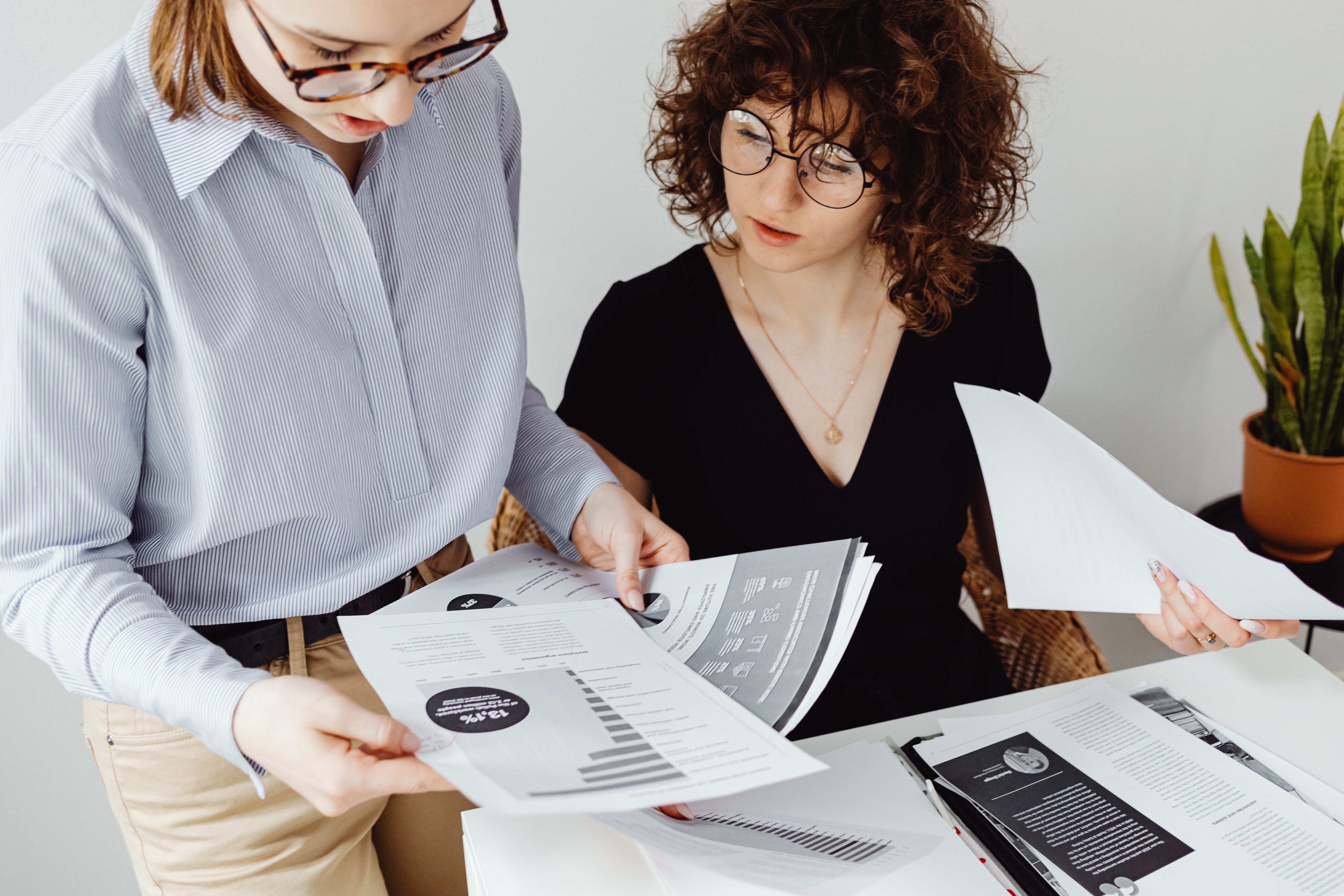 Two women looking at papers with data charts and graphs on them.
