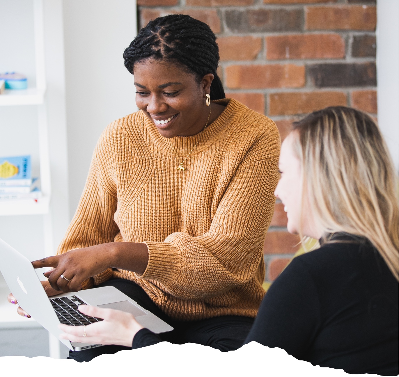 A career support specialist points at a laptop screen while working with a student to improve her job search.