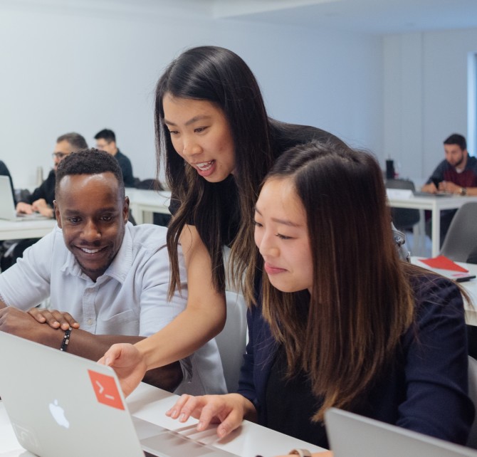 A Juno instructor helping two students in a classroom