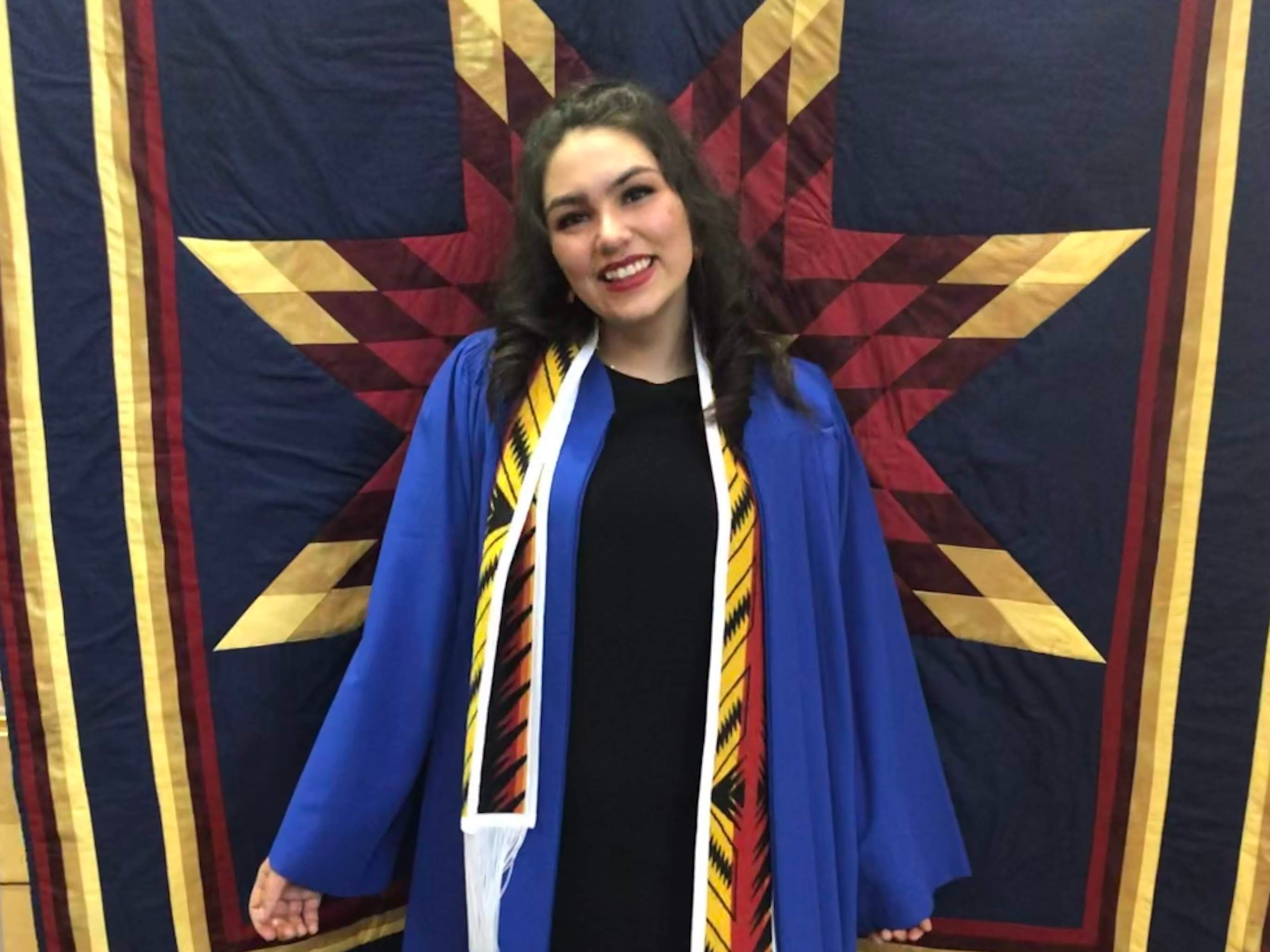 Photo of Candace smiling in her graduation gown 

