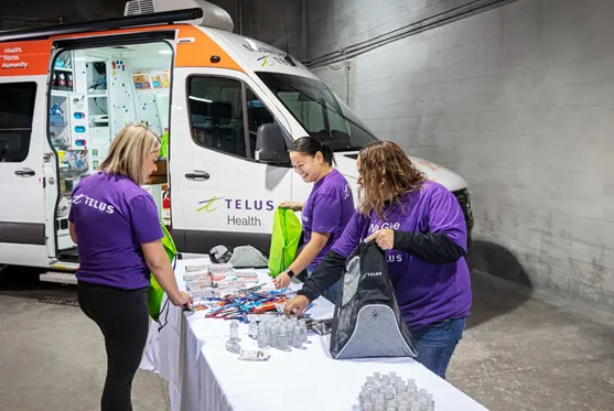 TELUS Team Members helping pack The Alex ‘Holiday Hope Totes’ full of toiletries, warm clothing, food and grocery gift cards.