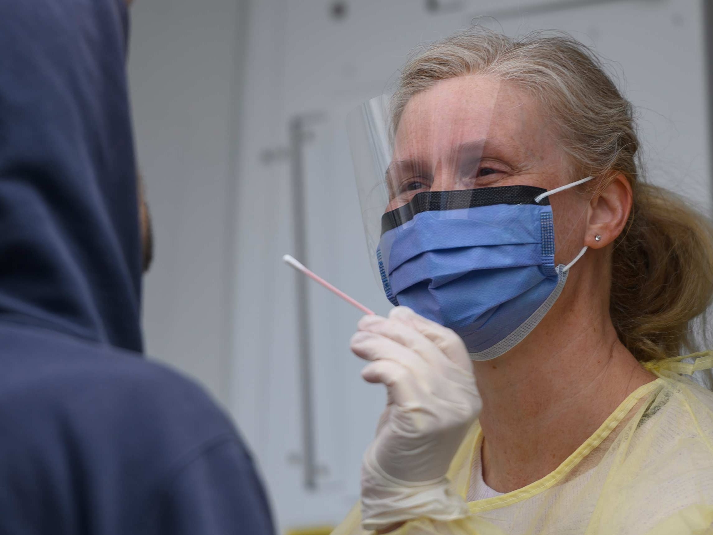 A nurse in personal protective gear administering a test.