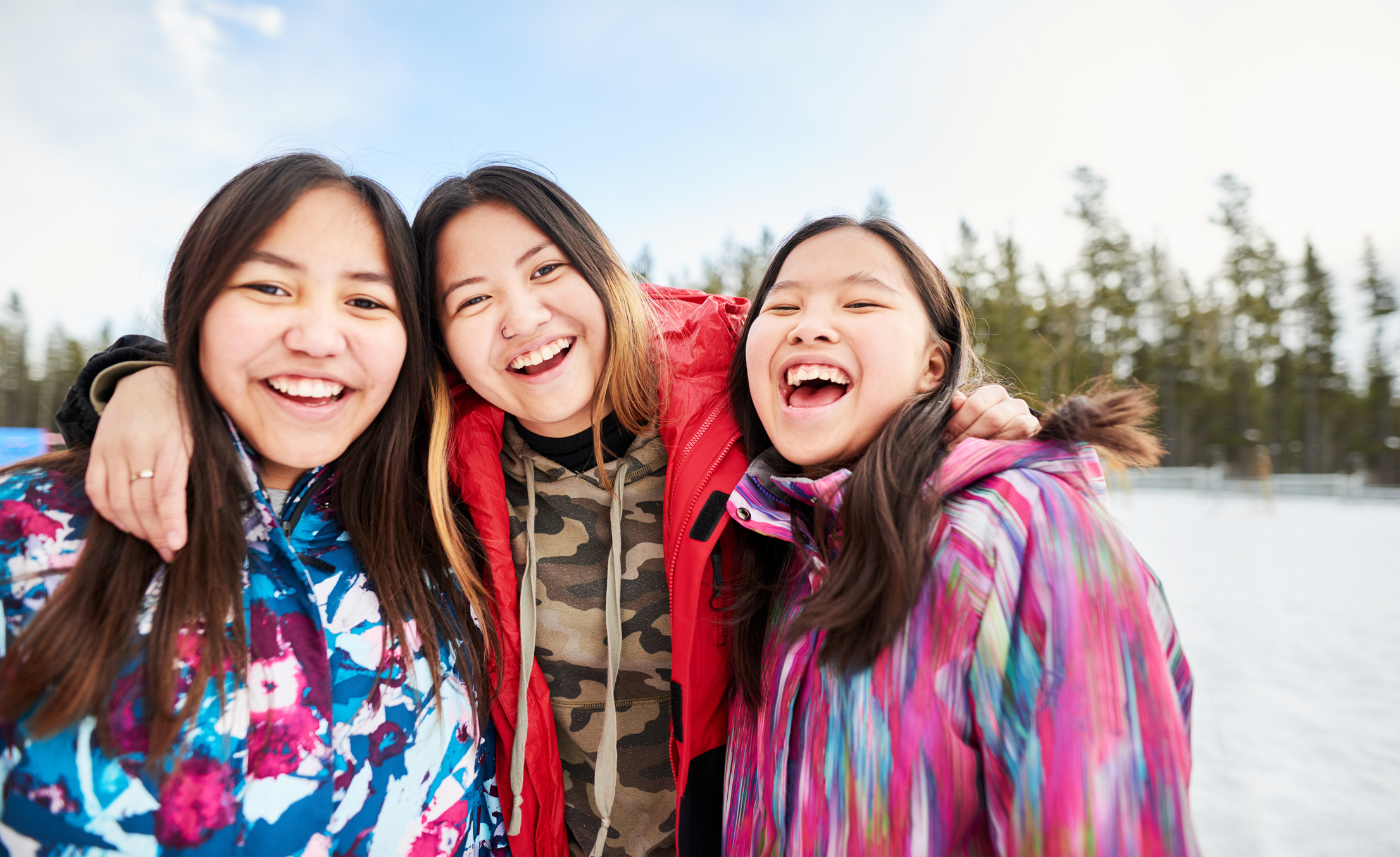 Three teenage girls laughing and smiling as they look forward to the future