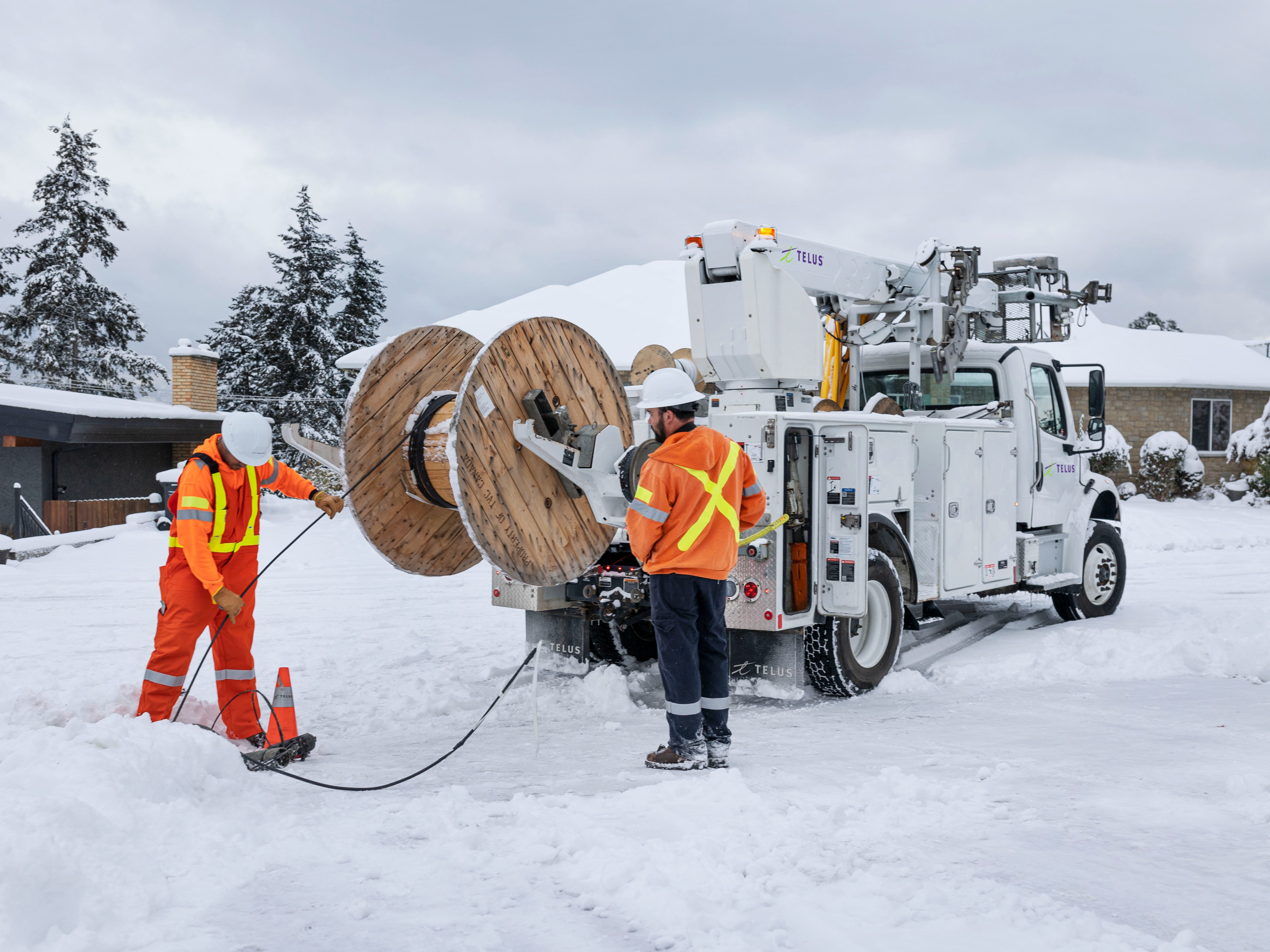 TELUS technicians removing retired copper cable from aerial lines.
 

