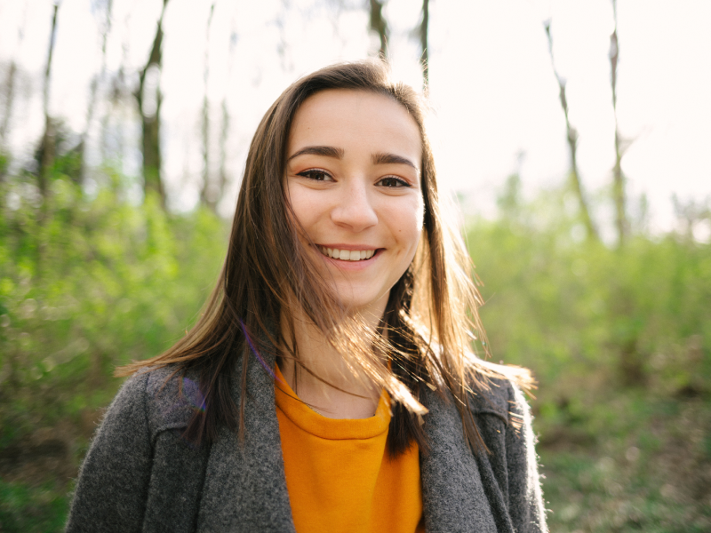 Une jeune femme souriant dans la nature.