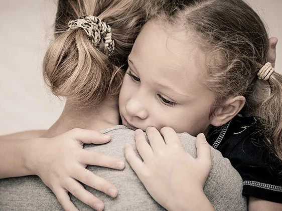 A young girl hugging a woman