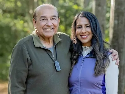 An elderly man and his daughter smile together on a wooded trail. He wears a discreet emergency pendant, demonstrating how medical alert systems for seniors Canada provide peace of mind and safety for active families enjoying the outdoors.