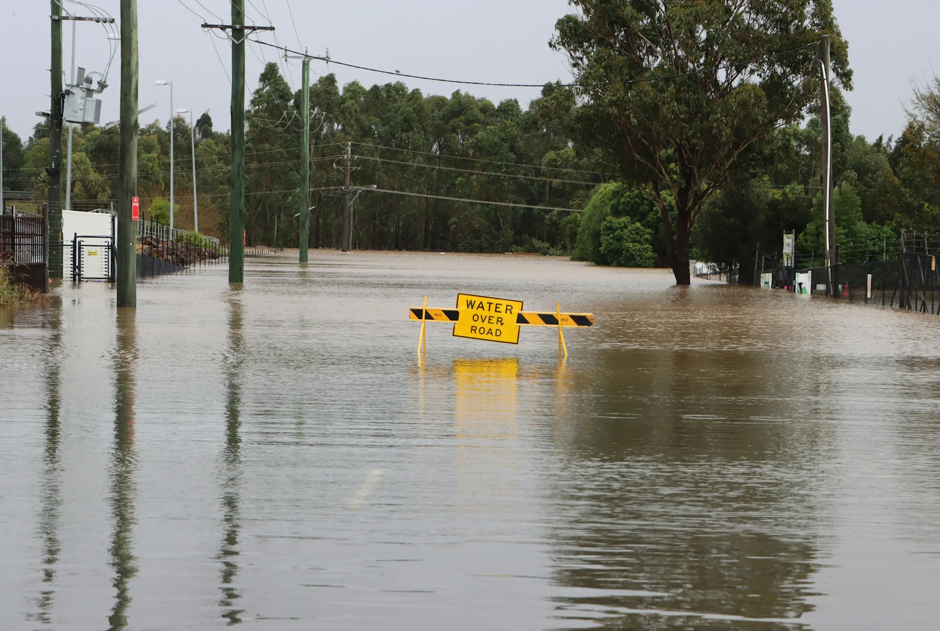 A flooded street with a yellow sign that reads “water over road.”
