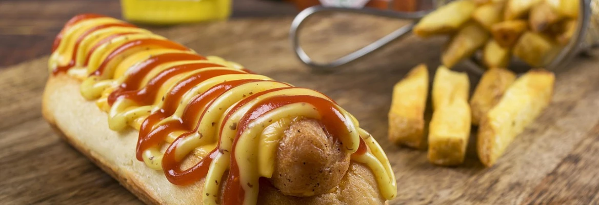 A hot dog dressed with ketchup and mustard next to some fries