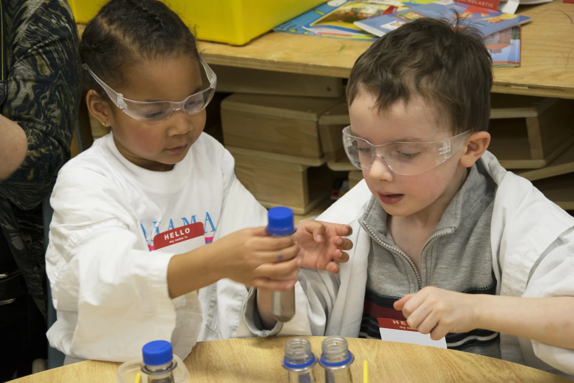 Young children in protective glasses holding test tubes, learning about science