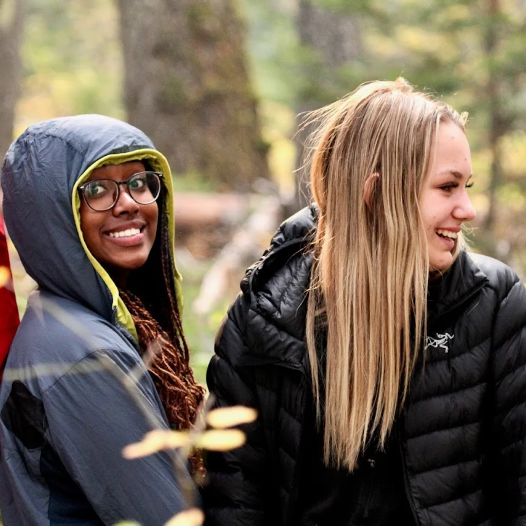 Two female youth smiling for the camera in nature.