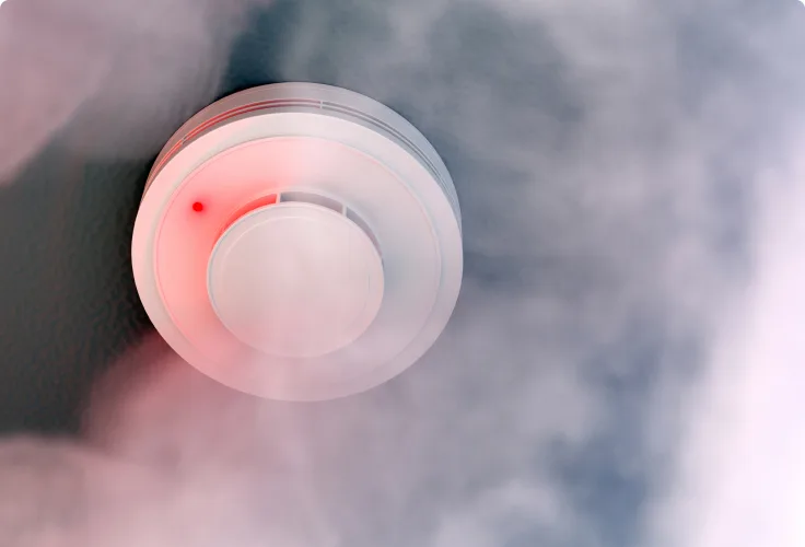 A smoke detector is shown within a cloud of smoke.