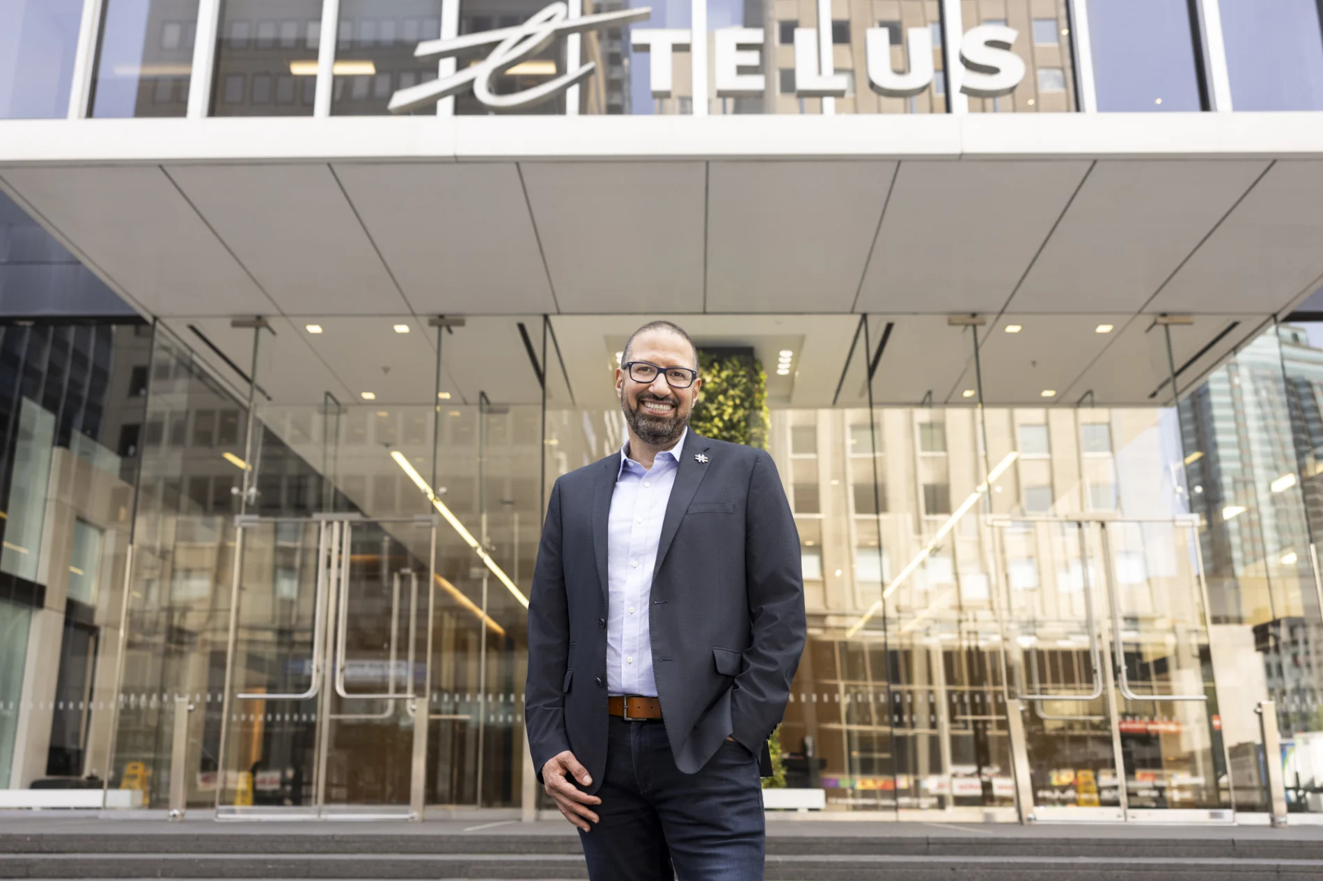 Nazim Benhadid, premier vice-président, Réseaux de TELUS, debout devant un immeuble TELUS.