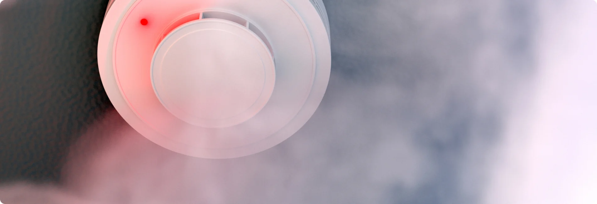A smoke detector is shown within a cloud of smoke.