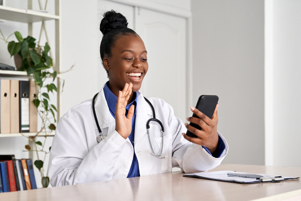 Professionnel de la santé en appel vidéo avec son téléphone portable, faisant signe à l'autre personne