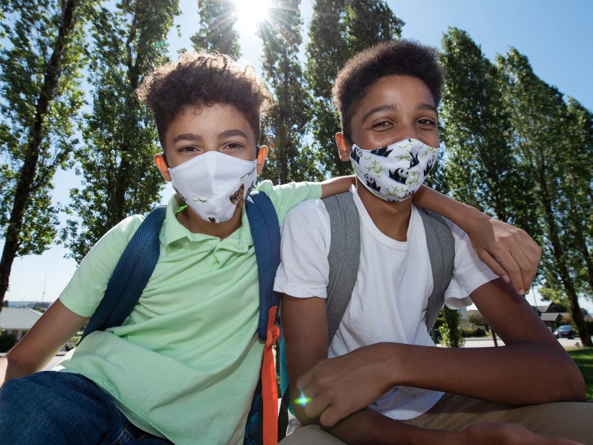 Two boy wearing a TELUS Critter face mask made with recycled and organic material