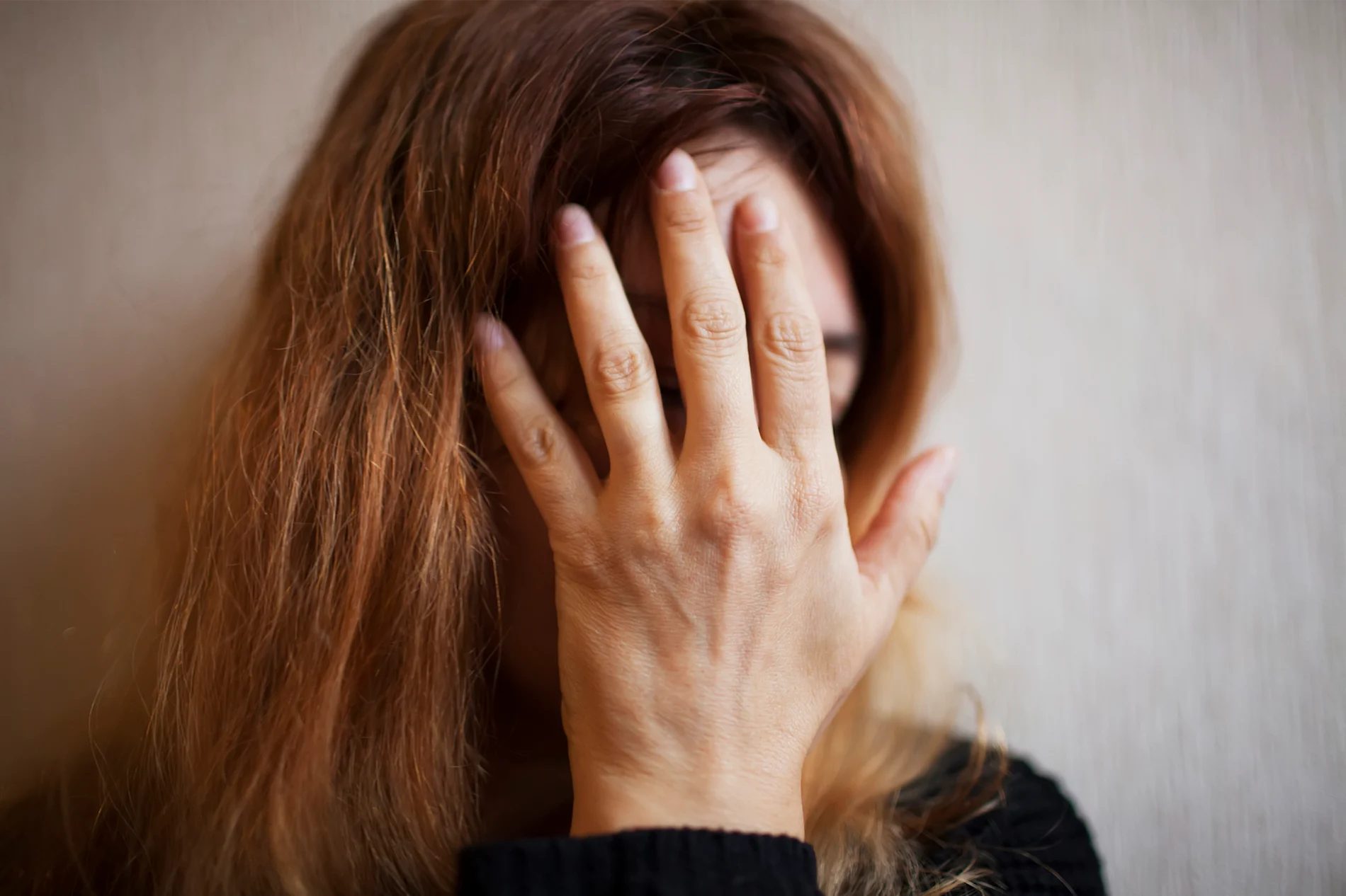 A woman covering her face with her hand.