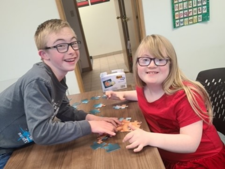 A boy and girl with Down syndrome playing inside the classroom. 