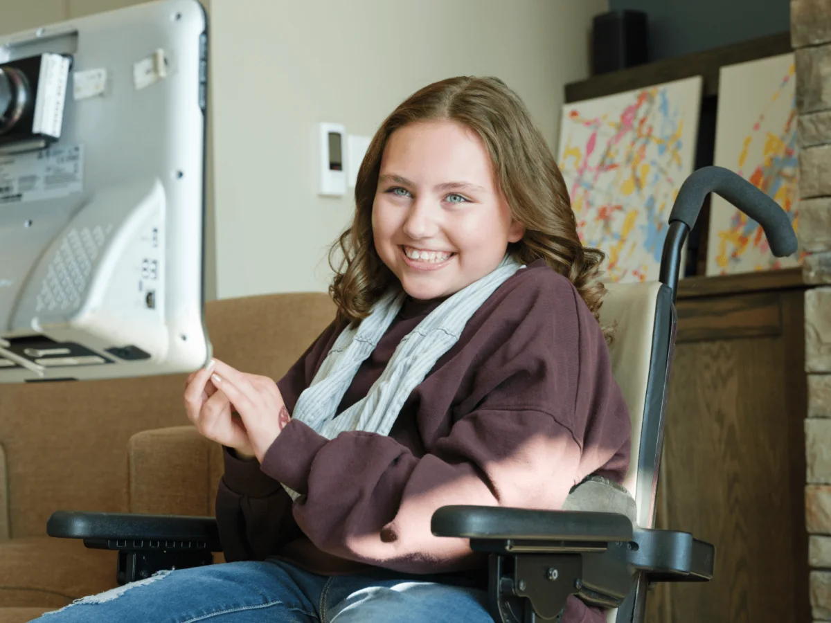 Olivia smiling in her wheelchair while using brain computer interface technology.