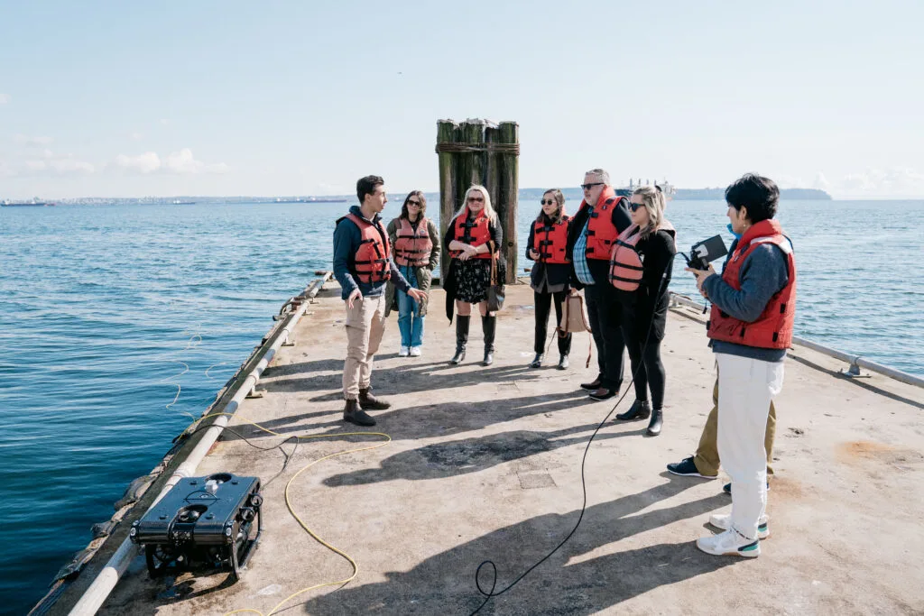 TELUS team members gathered by the water, learning about the technology used to monitor underwater ecosystems. 