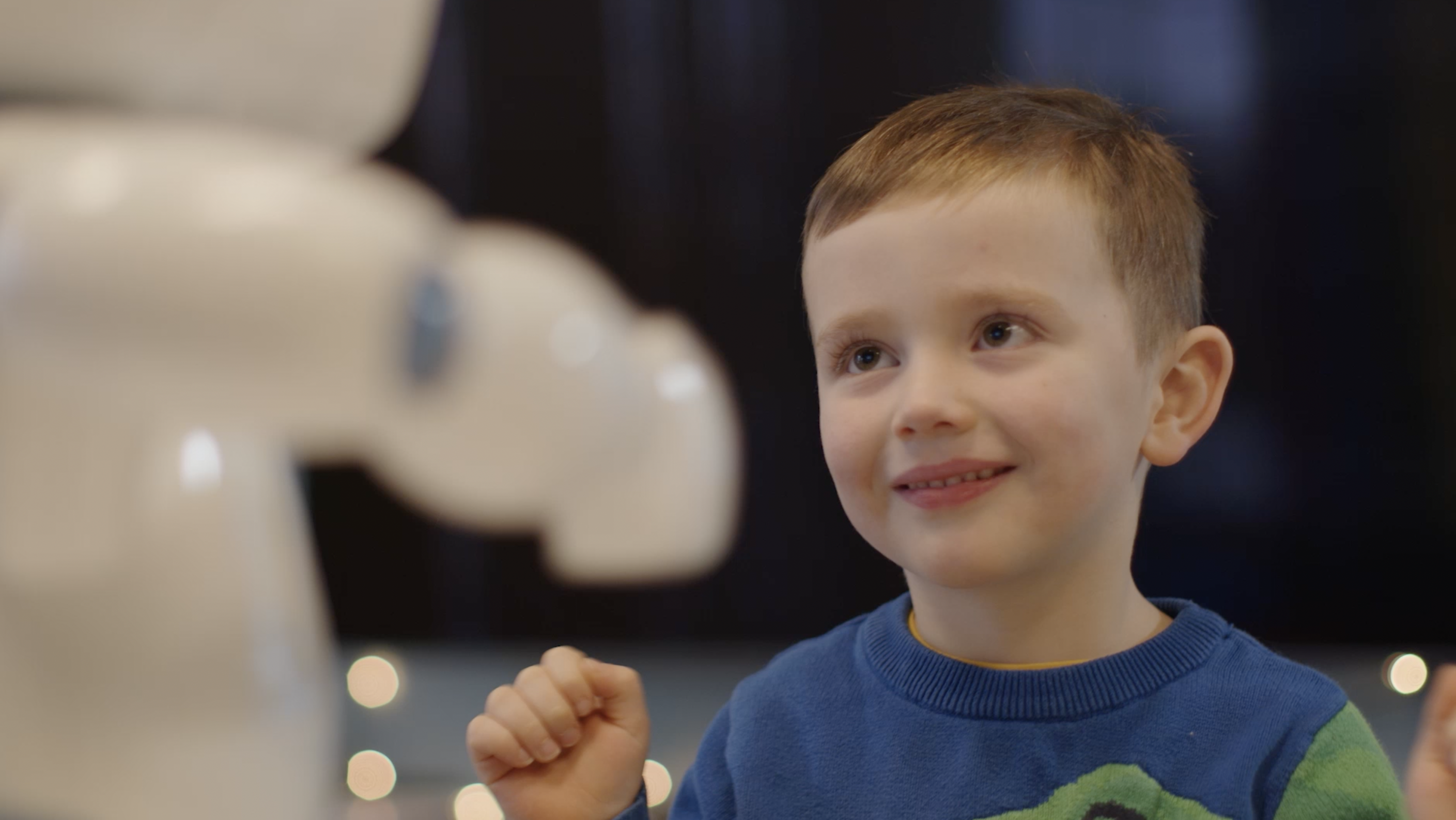 Another photo of a preschool age child in a Learning Disabilities Society program engaging with a social robot. 