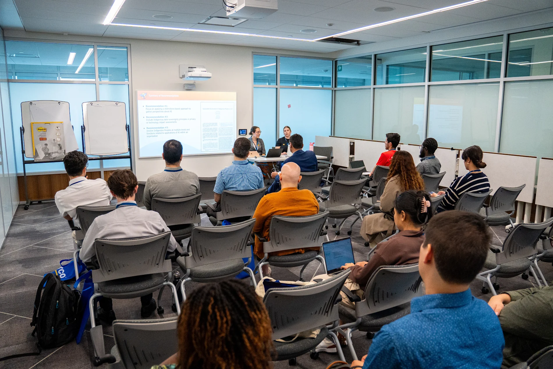 Kendal Burtch and Melanie Demers presenting in front of a room of people.
