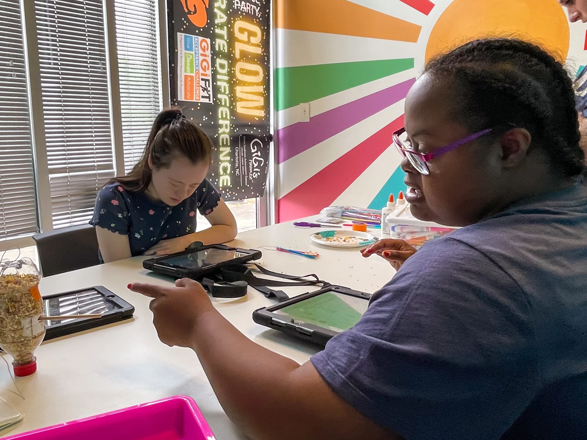 Two children sitting at a table and interacting with their tablets at Gigi’s Playhouse
