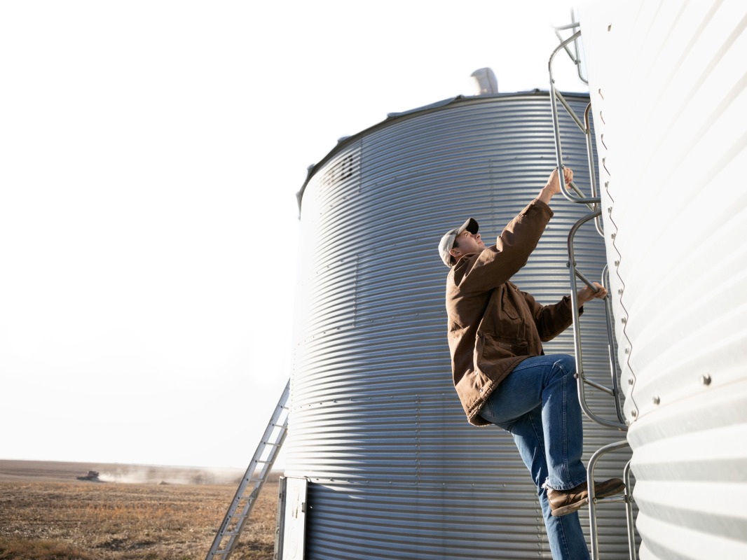 A farmer safely climbing up a silo.