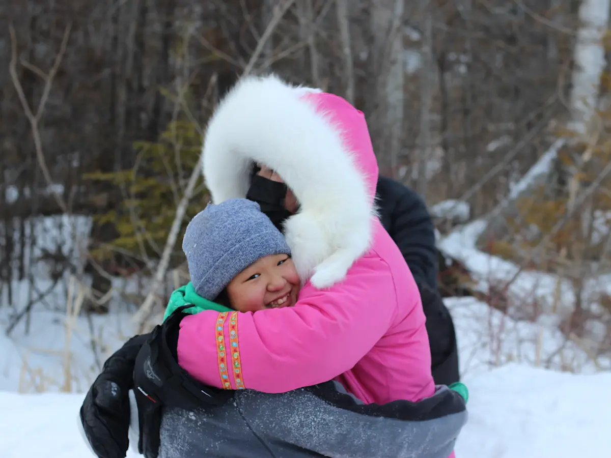 Two girls hugging outside in the snow