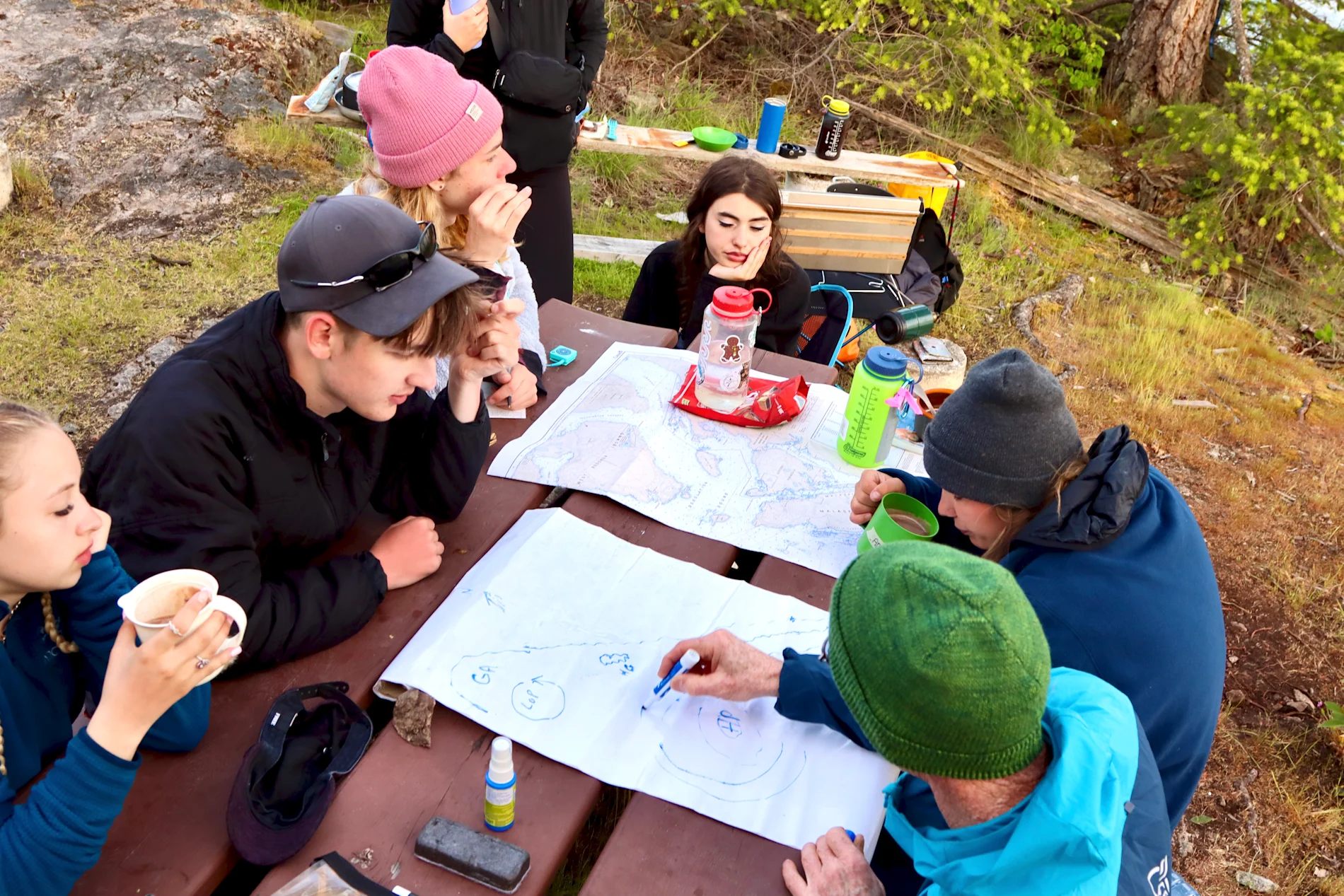 Students designing maps on a picnic bench.