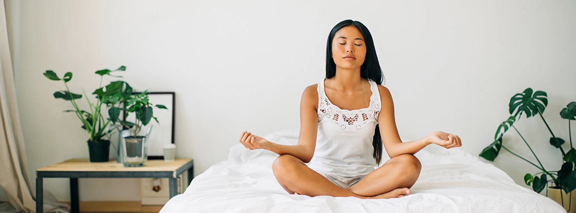 Young woman meditating on bed