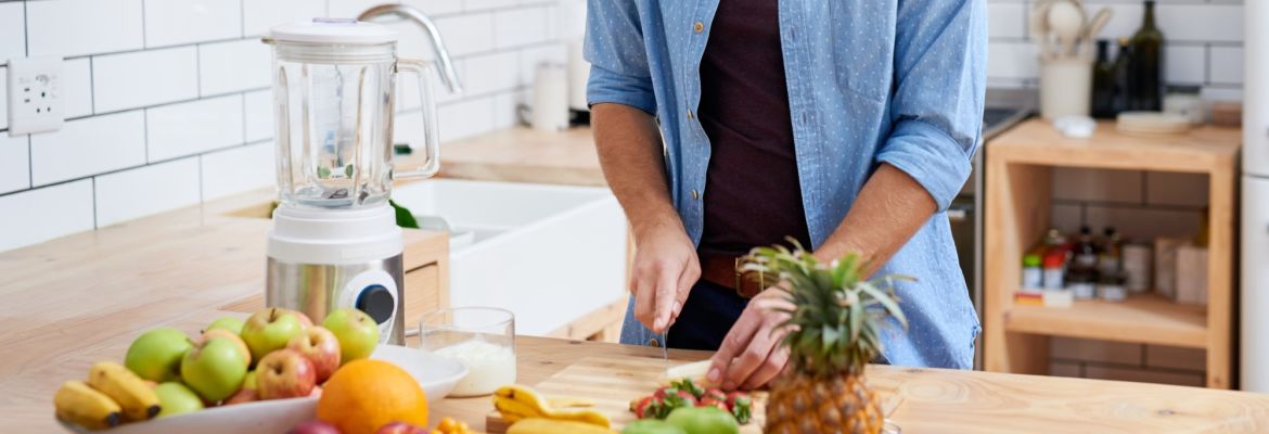 Man in kitchen chopping fruits, adopting healthy eating habits to help decrease his likelihood of experiencing memory decline.