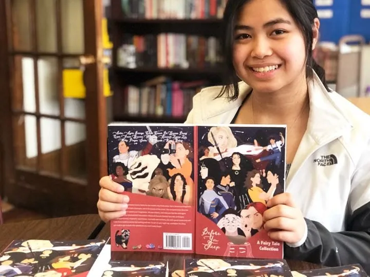 Young girl in library holding up a book