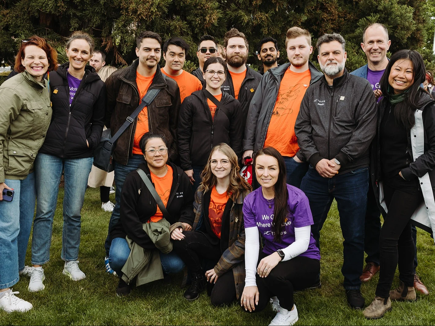 TELUS team members gather outside on an open field.