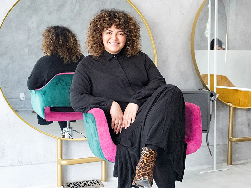 Solange Ashoori smiling as she sits in a chair.