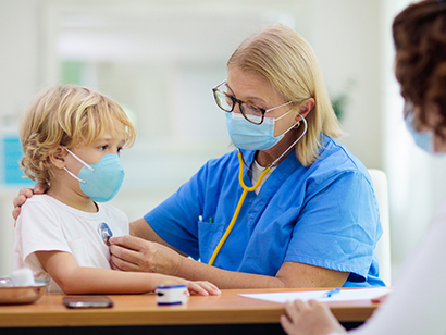 Une travailleuse de la santé écoute le rythme cardiaque d’un enfant à l’aide d’un stéthoscope.