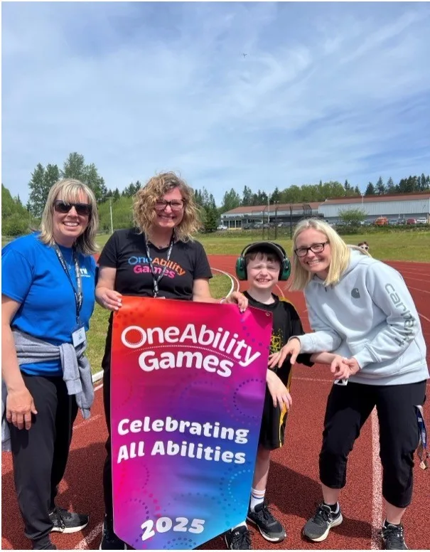 Staff members from OneAbility Games alongside a child and his mother holding up a sign that reads: OneAbility Games, celebrating all abilities, 2025.