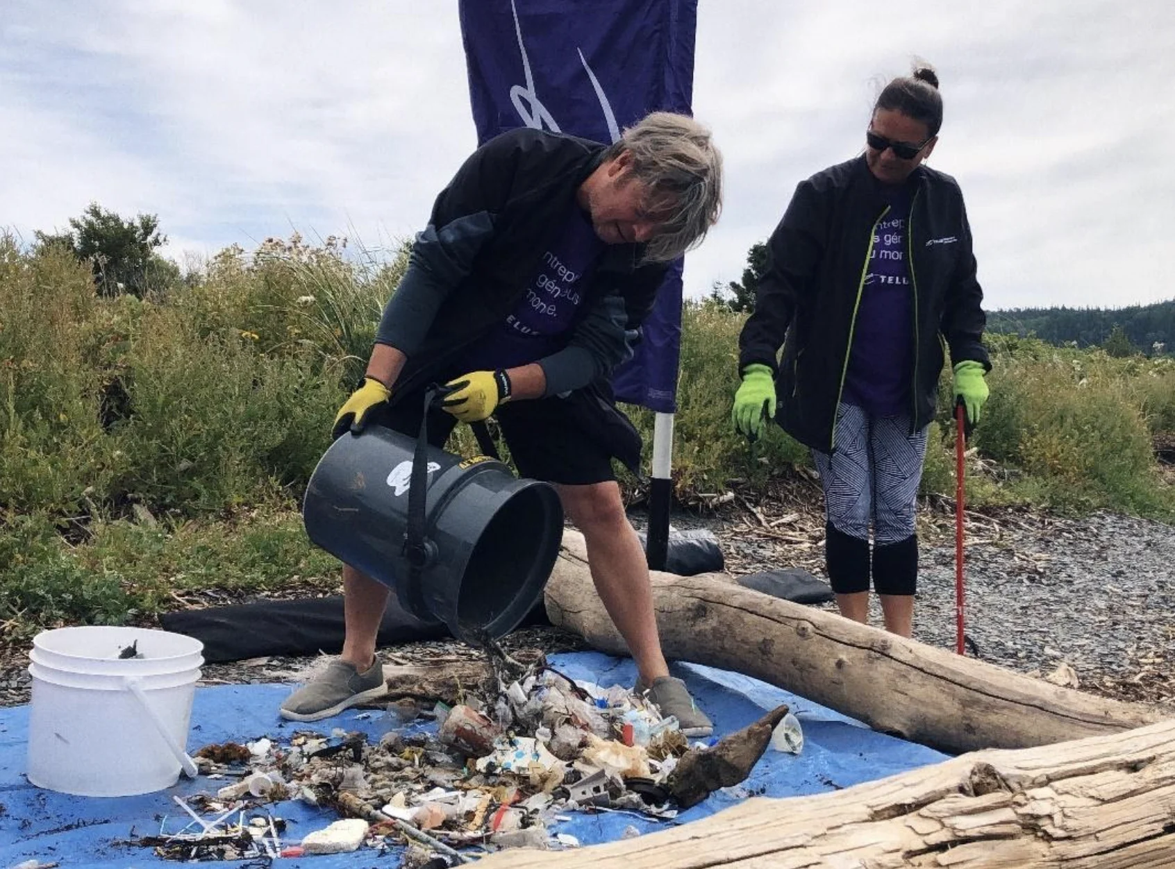 Volunteers in TELUS shirts cleaning up trash on the beach 