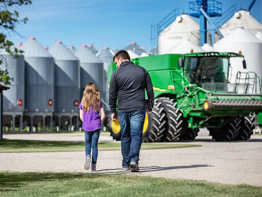 father and daughter holding hands walking on their farm